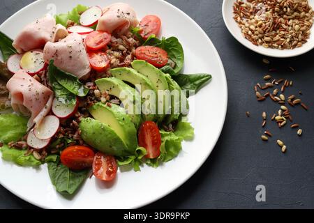 Frischer und gesunder Mischkornsalat mit Avocado, geschnittenem ​​turkey oder Huhn, Kirschtomaten, Radieschen, frischen Salatblättern und Baby-Spinat. Stockfoto
