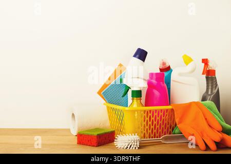 Sammlung von Reinigungsmitteln, die in einem Korb auf einer Holzoberfläche für Haushaltsaufgaben angeordnet sind Stockfoto