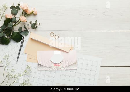 Sammlung von Artikeln für die Hochzeitsplanung auf einem Holztisch mit Blumenelementen Stockfoto