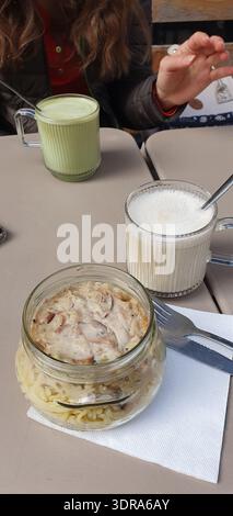 Telefonfoto des Mittagessens in einem veganen Café mit einem Freund, mit Pilznudeln in einem Glas, Chai Latte und Matcha Tee. Ungezwungene Dining-Szene mit h Stockfoto
