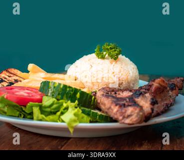 Hähnchenbraten in Nahaufnahme mit Tomatensalat und Pommes frites, Hähnchenbraten auf Holztisch, Teller mit Roa Stockfoto