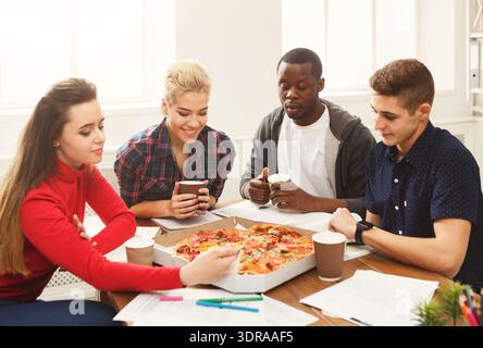 Vier Freunde versammeln sich an einem Tisch mit Pizza- und Kaffeetassen Stockfoto
