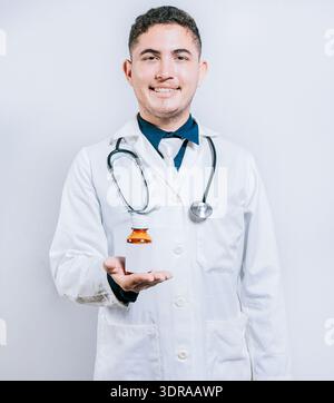 Lächelnder junger Arzt zeigt eine Flasche Sirup. Arzt zeigt eine Flasche Sirup Stockfoto