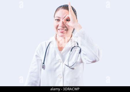 Fröhliche Ärztin-Gesten-Zustimmung isoliert. Junge Ärztin mit Finger auf isoliertem Hintergrund Stockfoto