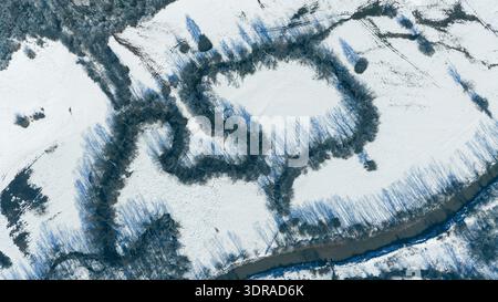 Die winterliche Landschaft mit einem sich windenden Fluss, der durch schneebedeckte Berglandschaft fließt Stockfoto