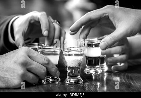 Schüsse auf einer Bartheke. Mehrere Alkoholgläser. Set mit Cocktails. Schwarz-weiß Stockfoto