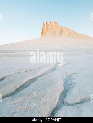 Blick auf die Kreideberge, die sich vom strukturierten, weißen Wüstenboden unter einem ruhigen Himmel erheben und einen starken, aber schönen Kontrast schaffen, Aktau, Mangystau Reg Stockfoto