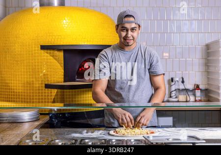 Man Cook bereitet eine Pizza in einem italienischen Restaurant Pizzeria zu. Essen, Küche, italienische Küche, Kochkonzept. Der Koch macht Pizza mit den Händen Stockfoto