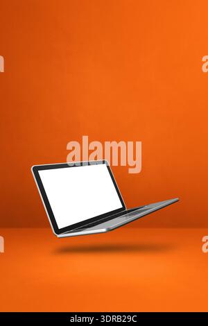 Schwimmender Computer Laptop isoliert auf Orange. Vertikaler Hintergrund Stockfoto
