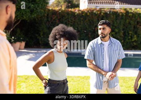 Verschiedene Freunde unterhalten sich und genießen an sonnigen Tagen Treffen im Freien am Pool Stockfoto
