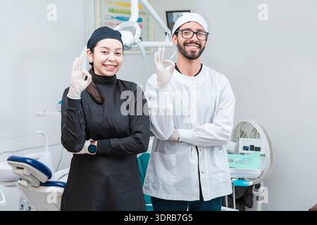 Porträt der Zahnärztin und ihrer Assistentin im Büro, Zahnärztin und ihrer Assistentin Daumen hoch, orale Profis Porträt Stockfoto