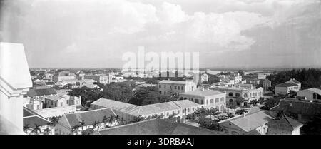 Ein Panoramafoto von 1906 bis 1907 zeigt Haiphong vom Dächer der Kathedrale aus mit einem V-förmigen Blick auf die Rue Paul Bert. Das Bild zeigt Lagerhauskomplexe, Wohnviertel einschließlich Wohnungen für Johan George Mulder aus Speidel & Co., Straßenaufteilung, koloniale Stadtplanung und Gewerbe- und Wohnarchitektur aus dem frühen 20. Jahrhundert in Nordvietnam. Stockfoto