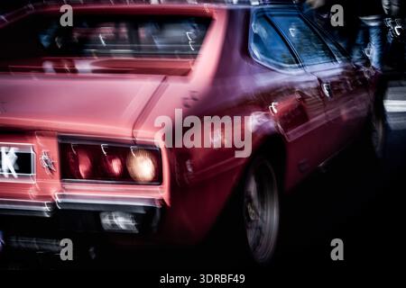 Bewegungsunscharfe Rückansicht eines klassischen roten Sportwagens, der während eines Fahrzeuges in Bewegung ist und Bewegung, Energie und Motorsport-Atmosphäre vermittelt. Stockfoto