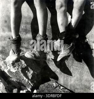 Dieses Nahaufnahme-Foto zeigt zwei Paar Beine und Füße während des niederländischen Hungerwinter in Amsterdam, 1944-1945. Einige Schuhe sind ohne Schnürsenkel, und ein Paar ist beschädigt, wenn sich die Sohlen lösen. Das Bild veranschaulicht die schwere Armut, den Mangel an angemessener Kleidung und die Auswirkungen der Verknappung im Krieg auf das tägliche Leben. Fotograf: Emmy Andriesse dokumentiert die materiellen Schwierigkeiten, denen die Einwohner Amsterdams während des Zweiten Weltkriegs gegenüberstanden Stockfoto