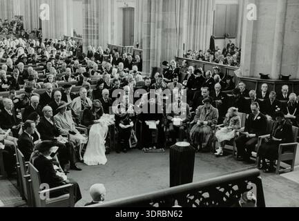 Dieses Foto zeigt die Taufe von Prinzessin Marijke am 9. Oktober 1947 in der Domkerk, Utrecht, Niederlande. Königin Wilhelmina, Prinz Bernhard und Prinzessin Juliana sitzen mit dem getauften Kind in der ersten Reihe. Kardinal de Jong steht hinter Juliana, Großherzog und Herzogin von Luxemburg stehen neben Wilhelmina und Juliana. Das Bild zeigt die königliche Anwesenheit, das zeremonielle Protokoll, das Kircheninnere und die offiziellen religiösen Beobachtungen. Stockfoto