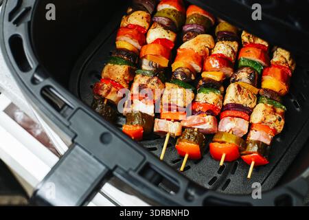 Gegrillte Fleisch- und Gemüsespieße in der Luftfritteuse aus der Nähe. Hausgemachte Barbecue-Art und gesunde Mahlzeit-Zubereitung Konzept. Stockfoto