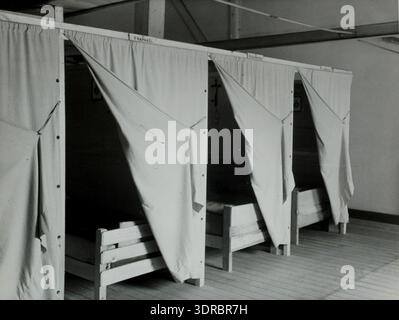 Dieses Foto zeigt den gemeinsamen Schlafsaal des Abdij van Achel, auch Achelse Kluis genannt, in Belgien am 11. Juli 1946. Der Raum verfügt über einfache, strenge Betten, die in Reihen angeordnet sind und das Leben der Trappisten widerspiegeln, in dem Essen, Lernen, Beten und Schlafen gemeinschaftlich sind. Das Bild veranschaulicht die klösterliche Betonung auf Einfachheit, gemeinsame Wohnräume und disziplinierte tägliche Routinen innerhalb der Abtei. Das Arrangement des Schlafsaals demonstriert das trappistische Prinzip des kollektiven und minimalistischen Lebensstils. Stockfoto