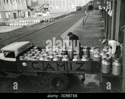 Dieses Archivfoto zeigt die niederländische Textilindustrie am 7. April 1938 und zeigt die Wollproduktion aus Milch (Casein) in Casenka oder AKU. Eine Milchlieferung durch einen Milcharbeiter liefert den Rohstoff. Maschinen, Lager, Verarbeitung und Arbeiter veranschaulichen industrielle Techniken, chemische Textilverarbeitung und Fabrikbedingungen in den 1930er Jahren in den Niederlanden. Stockfoto