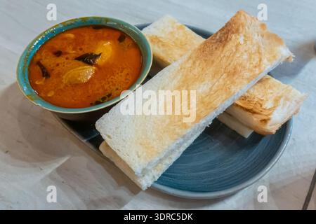 Malaysisches Frühstück bestehend aus geröstetem Brot und Hühnercurry zum Dippen, Kitchen by Openhouse Restaurant, Kuala Lumpur Airport, Malaysia Stockfoto