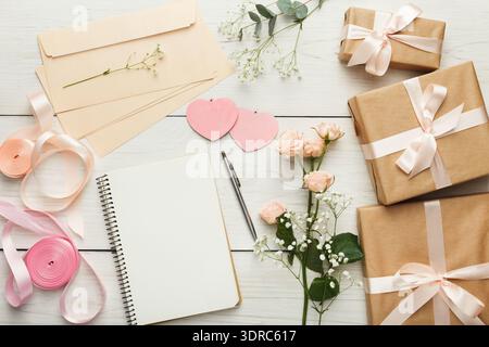 Geschenkverpackung und Vorbereitung auf eine besondere Feier mit Blumen und Briefpapier Stockfoto