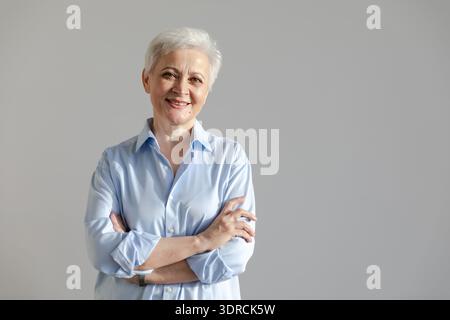 Selbstbewusste, stilvolle europäische Seniorin mittleren Alters. Ältere, reife Dame aus den 60er Jahren lächelnd auf weißem Hintergrund. Glückliche attraktive Seniorin Stockfoto