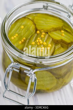 Scheiben eingelegte Gurken mit Senf in einem Glas. Vorspeise für Feinschmecker. Eine Zutat für die Zubereitung von Sandwiches und Salaten. Selektiver Fokus Stockfoto