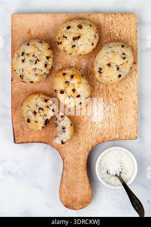 Frisch gebackene hausgemachte Kekse (Kekse) mit Kokos- und Schokoladentropfen auf einem Holzbrett auf Marmorhintergrund. Köstlich c Stockfoto