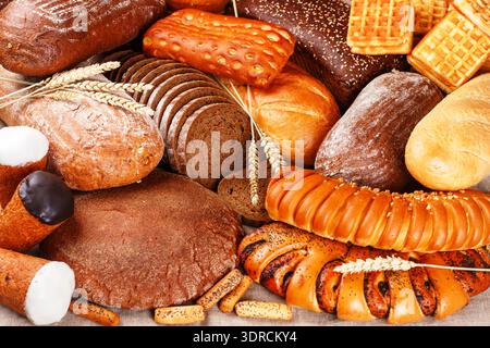 Frisch gebackenes Roggen- und Weizenbrot auf dem Tisch. Ganze und geschnittene Brote. Lebensmittelkonzept Stockfoto