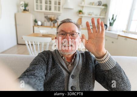 Glücklicher älterer Mann mittleren Alters, der mit Freunden und Familie im Videoanruf spricht. Lachender reifer, alter Großvater, der Spaß hat, zu sprechen Stockfoto