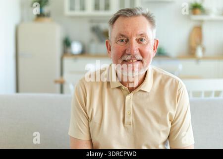 Selbstbewusster, stilvoller Seniorenmann mittleren Alters zu Hause. Älterer reifer Mann der 70er Jahre lächelt. Glücklicher attraktiver Seniorbart, der Großvater guckt Stockfoto