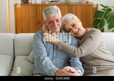 Älteres erwachsenes Ehepaar umarmt zu Hause. Alter Mann und Frau im mittleren Alter, die sich mit Zärtlichkeit umarmen, lieben es, süße Bindungen zu genießen Stockfoto