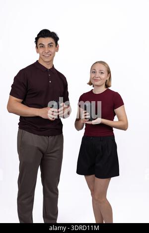 Junger Mann und Frau, die gemeinsam im Studio Smartphones benutzen Stockfoto