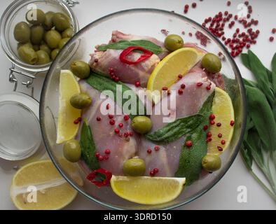 Rohes Kaninchen und Gewürze - Zitrone, Salbei, Pfeffer, Lorbeerblatt, Oliven Stockfoto