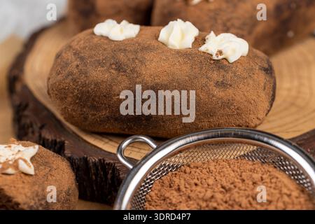 Süße braune Teigkartoffeln liegen auf Servierbrett und Papier, süßer klassischer Kuchen aus Butter und eine große Menge Kakao gemischt mit Biskuitkuchen Stockfoto