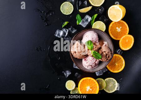 Eis in einer Schüssel mit Zitrusfrüchten und Eis auf dunkler Oberfläche Stockfoto