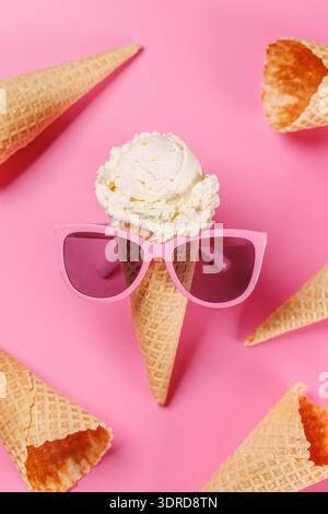 Ein verspielter Eisbecher mit stylischer Sonnenbrille vor einem leuchtend rosa Hintergrund Stockfoto