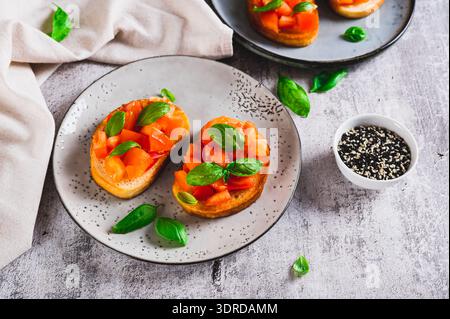 Italienische Sandwiches mit Tomaten, Basilikum und Knoblauch auf einem Teller auf einem Tisch Stockfoto