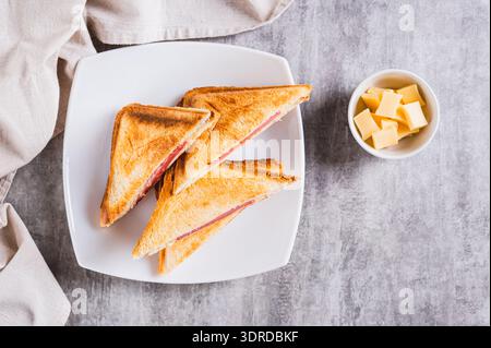 Gegrillte Dreieck-Sandwiches mit Käse und Wurst auf einem Teller auf einem Tisch mit Blick von der Tischplatte Stockfoto