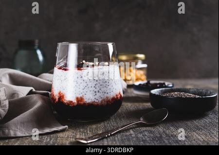 Chia Pudding mit Joghurt und Johannisbeermarmelade in einem Glas auf dem Tisch Stockfoto