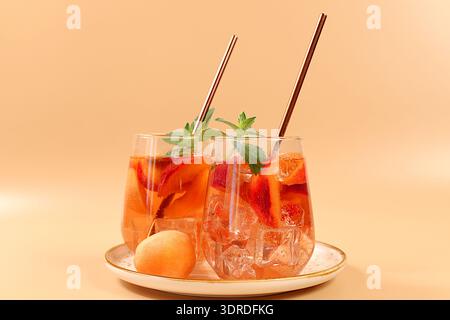 Eis-Pfirsichtee oder Cocktail mit Minze und Aprikosen, ein Rezept für ein erfrischendes Sommergetränk. Zwei Gläser mit Pfirsichfrucht-Limonade Stockfoto