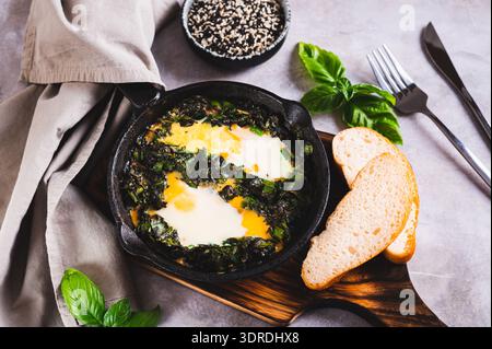 Grün gebackene Shakshuka mit Kräutern in einer Pfanne auf dem Tisch Stockfoto