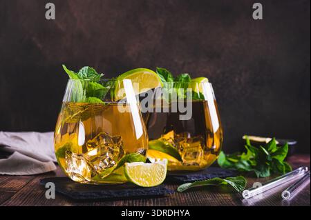 Erfrischender Eistee mit Pfefferminze und Limette in Gläsern auf dem Tisch Stockfoto