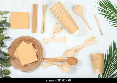 Ein Set umweltfreundlicher Gerichte auf einem sonnigen Tisch. Pappbecher, Teller, Kraftpapierservietten, Barbecue-Strohhalme, Holzgabel Stockfoto