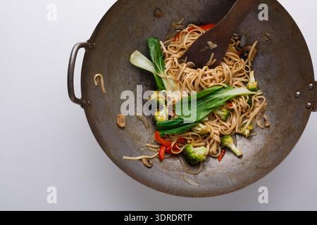 Köstlicher Rührbraten mit Nudeln und Gemüse in einem großen Wok auf einem weißen Tisch Stockfoto