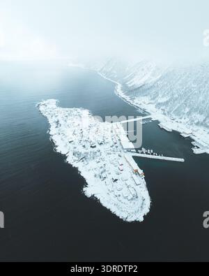 Aus der Vogelperspektive eines schneebedeckten Dorfes auf einer kleinen Insel neben den Fjorden, von oben in Husøy, Vestfold, Norwegen. Stockfoto