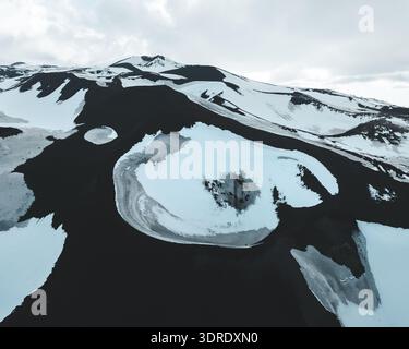 Aus der Vogelperspektive des starken Kontrastes zwischen der dunklen vulkanischen Erde und dem unberührten weißen Schnee, der eine dramatische, strukturierte Landschaft schafft, Linguaglossa, Stockfoto