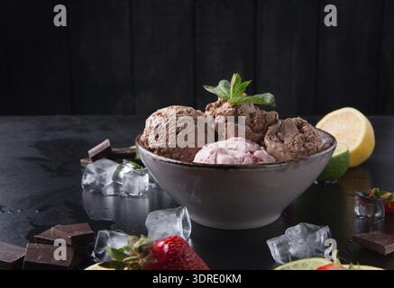 Verschiedene Geschmacksrichtungen von Eis in einer Schüssel mit frischem Obst und Schokoladenstückchen Stockfoto