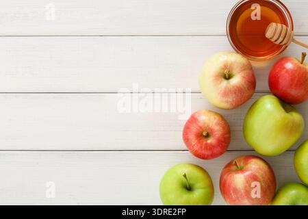 Verschiedene Arten von Äpfeln, die mit Honig auf einem Holztisch angeordnet sind Stockfoto