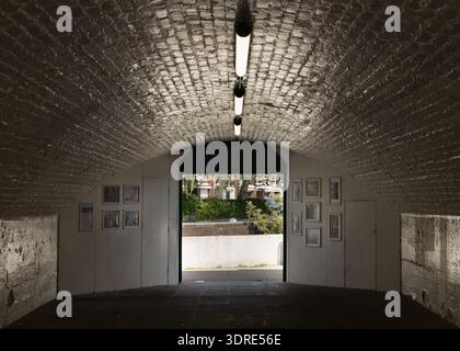 London, Großbritannien - 16. Juni 2025 - das Innere einer historischen Backsteinunterführung unter der Kew Bridge, heute als intimer Galerieraum umfunktioniert. Die Struktur Stockfoto