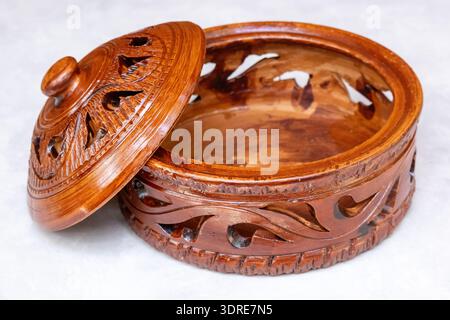 Eine offene handgefertigte dekorative Töpferdose mit Deckel. Dieser traditionelle, handwerklich hergestellte runde Aufbewahrungsbehälter verfügt über komplizierte geometrische Ausschnitte Stockfoto